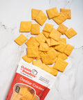Gluten-free cheddar crackers from Outside The Breadbox with packaging and crackers displayed on a marble background