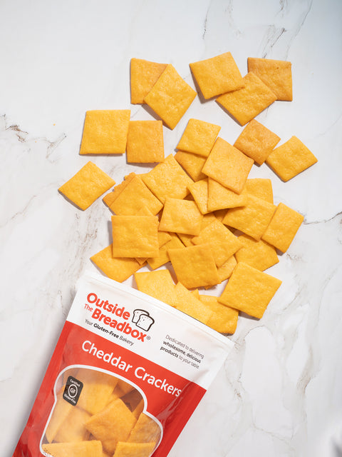 Gluten-free cheddar crackers from Outside The Breadbox with packaging and crackers displayed on a marble background