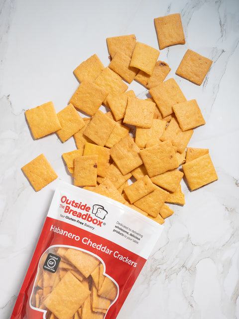 Gluten-free habanero cheddar crackers from Outside The Breadbox with bag and crackers scattered on a white surface