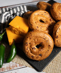 Gluten-free jalapeño cheddar bagels with fresh jalapeños and cheddar cheese on a serving board