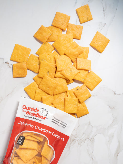 Gluten-free jalapeño cheddar crackers from Outside The Breadbox with crackers scattered next to the package