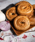 Rustic display of gluten-free savory bagels on a wooden board with sliced onion