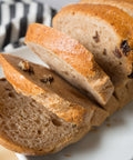 Vegan oat cinnamon raisin gluten-free bread loaf on serving board with cinnamon and raisins