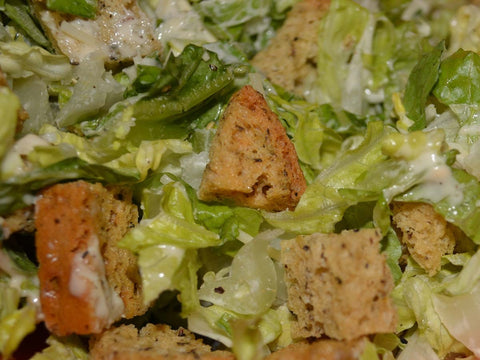 Gluten-free herb croutons added to a fresh green salad, showing toasted texture and seasoning