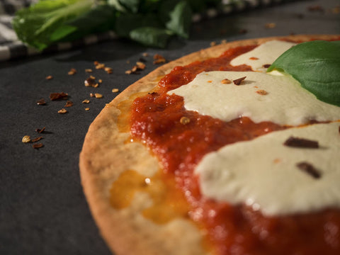 Close-up of gluten-free margherita pizza with tomato sauce, melted mozzarella, and fresh basil on a crisp crust