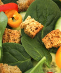 Gluten-free croutons tossed with fresh spinach, cucumber, and sliced bell peppers in a salad